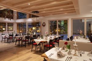 een restaurant met witte tafels, stoelen en ramen bij Jägerhof Serviced Apartements in Zermatt