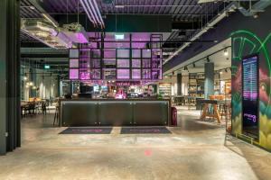 une grande chambre avec un bar et quelques tables dans l'établissement Moxy London Heathrow Airport, à Hounslow