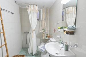 a white bathroom with a sink and a shower at Art apartment in Ancient Epidavros