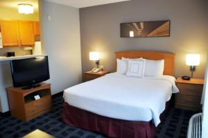 a hotel room with a bed and a flat screen tv at TownePlace Suites by Marriott Albuquerque Airport in Albuquerque