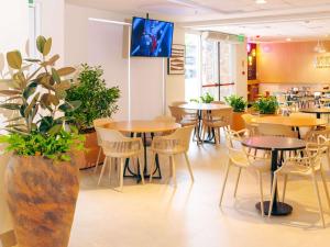 a dining room with tables and chairs and a plant at ibis Styles Goiania Marista in Goiânia