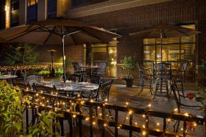 un patio avec des tables et des parasols éclairés dans l'établissement Sheraton St Paul Woodbury Hotel, à Woodbury