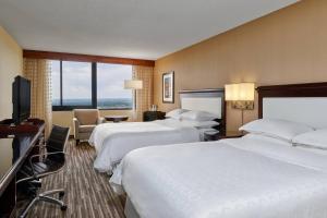 a hotel room with two beds and a flat screen tv at Sheraton Denver West Hotel in Lakewood