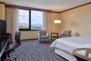 a hotel room with a bed and two chairs and a television at Sheraton Denver West Hotel in Lakewood