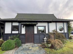 une petite maison blanche et noire avec une porte dans l'établissement Den Japanske Have B & B, à Herning