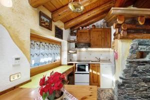 a kitchen with wooden cabinets and a table with flowers at Chalet L'Ange Des Neiges in Valtournenche