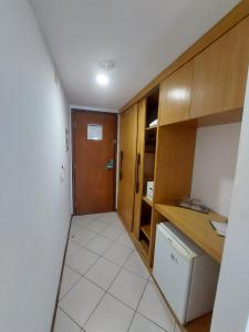 a kitchen with wooden cabinets and a white tile floor at Natal Plaza Suítes- Ponta Negra in Natal