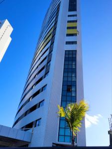 a tall building with a palm tree in front of it at Natal Plaza Suítes- Ponta Negra in Natal