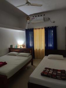 North ParavurにあるTakashi Homestay North Paravur Near Muzirisの青いカーテンが備わる客室のベッド2台