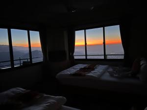 twee bedden in een kamer met uitzicht op de zonsondergang bij Hotel Pristine Himalaya in Pokhara