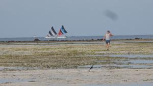 een vrouw die op het strand loopt met twee zeilboten bij Mola2 Resort Gili Air in Gili Air