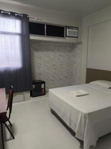 um quarto com uma cama branca e uma janela em Prestige Manaus Hotel em Manaus