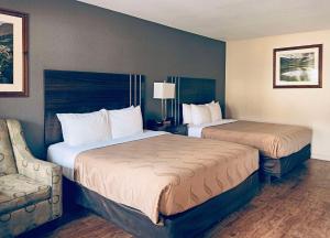 Quality Inn Durango في دورانجو: غرفة فندقية بسريرين وكرسي