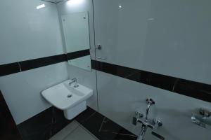 La salle de bains est pourvue d'un lavabo blanc et d'une douche. dans l'établissement Kailasam Residency, à Trivandrum