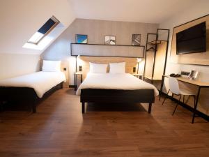 um quarto de hotel com duas camas e uma secretária em ibis Creil Sur Oise em Villers-Saint-Paul