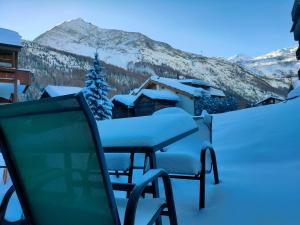 une table et des chaises recouvertes de neige sur un balcon dans l'établissement Studio 60m2 au pied de la télécabine et SaastalCards, à Saas-Fee