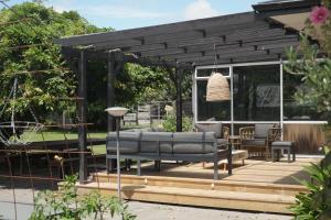 uma pérgola com um sofá num deque de madeira em Evendale House em Hastings