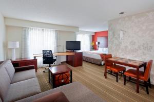 Residence Inn Lansing West في Delta Center Township: فندق غرفه بسرير وصاله