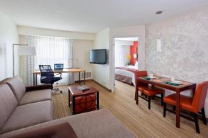 Residence Inn Lansing West في Delta Center Township: غرفة معيشة مع أريكة وغرفة مع سرير