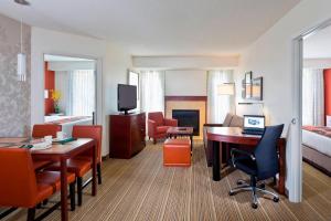 Residence Inn Lansing West في Delta Center Township: غرفة في الفندق مع مكتب وغرفة نوم