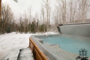 una vasca idromassaggio in un cortile coperto da neve di Le Loonix- Chalet familiale avec Spa a Petite-Rivière-Saint-François