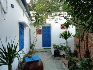 una casa blanca con puertas y plantas azules en Homestay Miền Biển Vĩnh Hy 2, en Vĩnh Hy