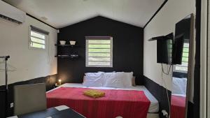 a small bedroom with a bed with a red blanket at Evasion Authentique en Tiny House - 1 Champagne OFFERT - Le Paradis des Petits Voyageurs in Le Diamant