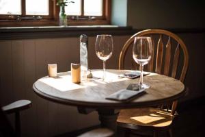 uma mesa de madeira com dois copos de vinho em The Chequers Inn em Rookley