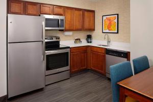 Residence Inn Saint Louis Airport / Earth City في مدينة ايرث: مطبخ مع أجهزة ستانلس ستيل ودواليب خشبية