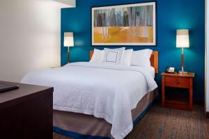 Residence Inn Saint Louis Airport / Earth City في مدينة ايرث: سرير كبير في غرفة فندق بجدران زرقاء