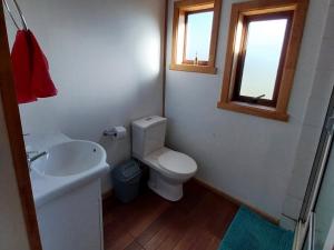 baño con aseo y lavabo y ventana en Rincón del Huape, en Curacautín