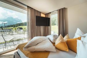 ein Schlafzimmer mit einem Bett mit Kissen und einem großen Fenster in der Unterkunft Ariane's Guesthouse in Sexten