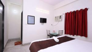 1 dormitorio con cama blanca y cortina roja en The NoVo Agra, en Agra