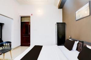 een slaapkamer met een bed, een stoel en een deur bij Hotel O IIDM ECO CENTRE in Lucknow