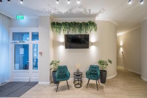 eine Lobby mit 2 Stühlen und einem TV an der Wand in der Unterkunft Baross City Hotel - Budapest in Budapest