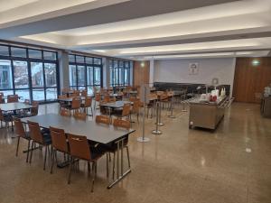 - une salle à manger avec des tables, des chaises et des fenêtres dans l'établissement Kolping Gästehaus, à Klagenfurt am Wörthersee