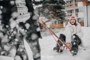 uma mulher está sentada na neve com esquis em Five Seasons Szklarska Poręba em Szklarska Poręba