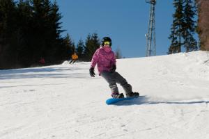 une femme faisant du snowboard sur une pente enneigée dans l'établissement Wellness hotel Sauna, à Malá Morávka