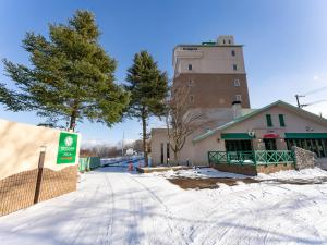 a building in the snow with a tower in the background at Tabist Shizukuishi Resort Hotel in Shizukuishi