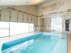 a large swimming pool with a large window at Tabist Shizukuishi Resort Hotel in Shizukuishi