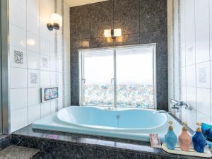 a blue tub in a bathroom with a window at Tabist Shizukuishi Resort Hotel in Shizukuishi