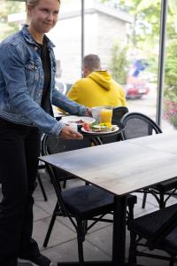 a woman standing next to a table with a plate of food at Strandnäs Hotell in Mariehamn