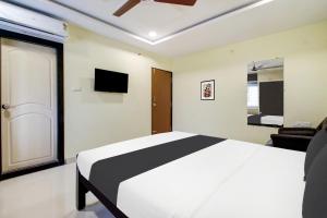 1 Schlafzimmer mit einem weißen Bett und einem TV in der Unterkunft Super Hotel O Murali Nagar Near NAD Junction in Visakhapatnam