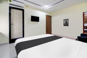 Schlafzimmer mit einem weißen Bett und einem TV in der Unterkunft Super Hotel O Murali Nagar Near NAD Junction in Visakhapatnam