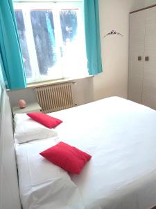 - une chambre avec 2 lits blancs et des oreillers rouges dans l'établissement Hotel B&B Lorenzini Ski, à Selva di Cadore