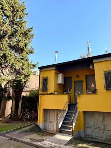 una casa amarilla con escaleras y un árbol en Gionas - Casa indipendente in zona strategica, en Milán