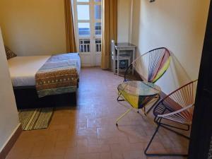 1 Schlafzimmer mit einem Bett, 2 Stühlen und einem Fenster in der Unterkunft Hôtel Niwa in Gorée