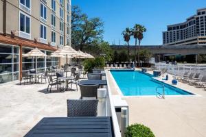 una piscina con mesas y sillas junto a un edificio en DoubleTree by Hilton Hotel Biloxi, en Biloxi