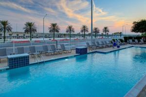 una gran piscina con sillas y palmeras en DoubleTree by Hilton Hotel Biloxi, en Biloxi