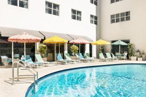 une piscine dans un hôtel avec des chaises et des parasols dans l'établissement Hotel Continental Miami Beach, Tapestry Collection by Hilton, à Miami Beach